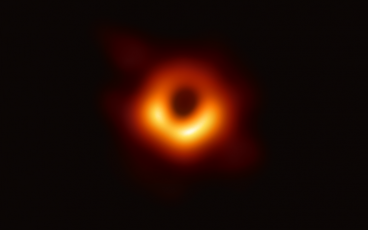Against a black background, a red-orange ring with an unmistakeable dark center. The ring is asymmetrically brighter on the bottom half than the top.