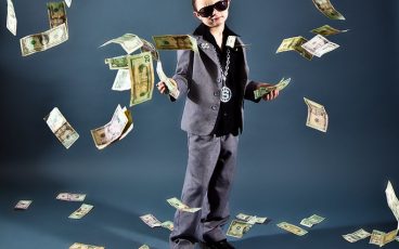 boy with stack of money and dollar bills falling from the ceiling